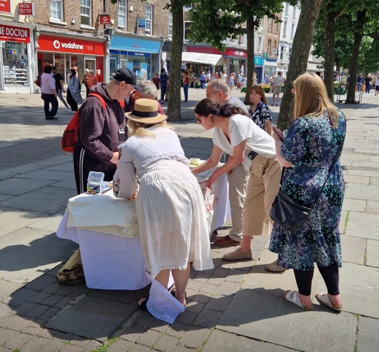 Group of people gathering in York centre around a table submitting feedback about the tourism levy.